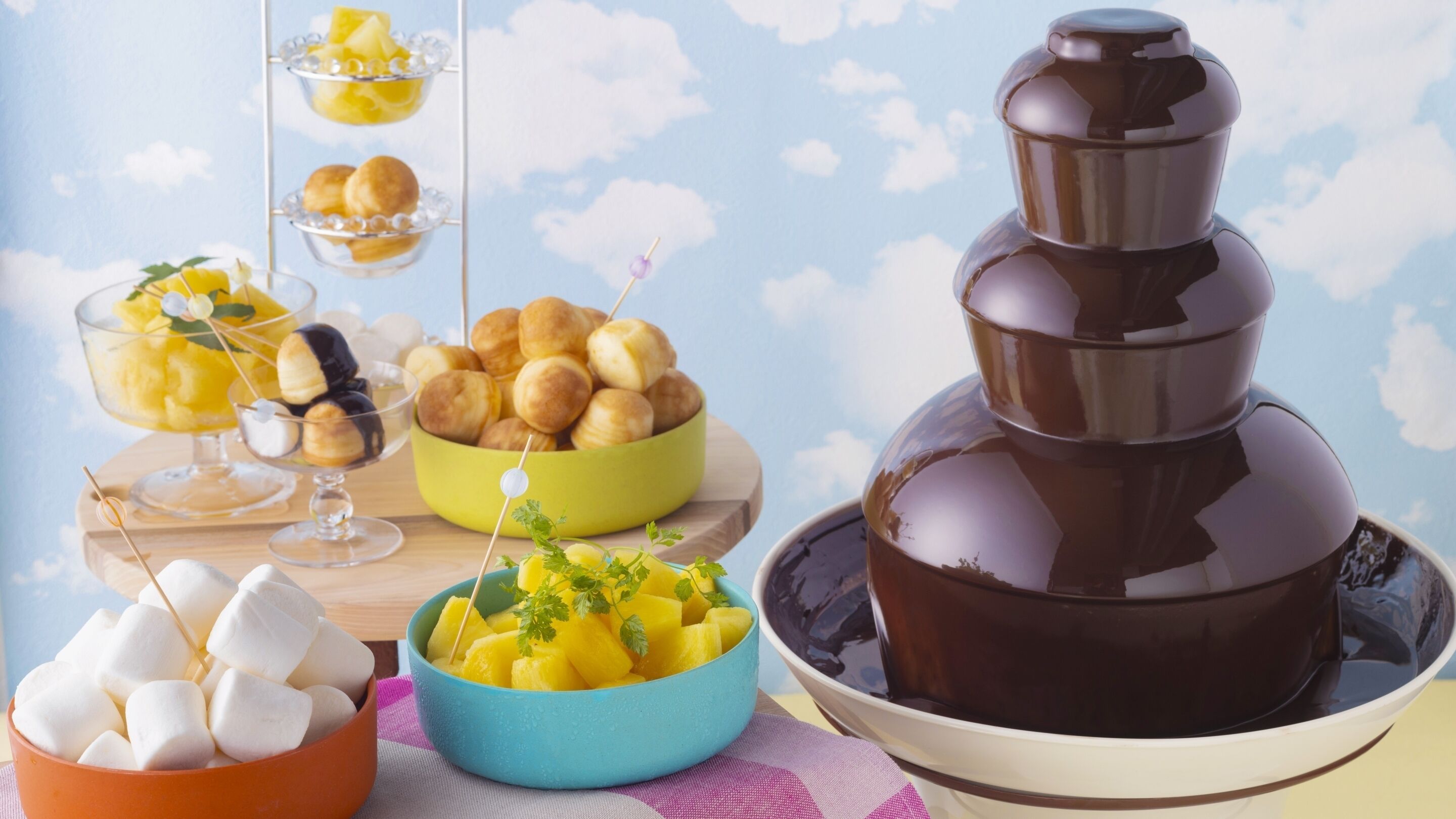 Una fuente de chocolate con malvaviscos, panecillos y fruta.