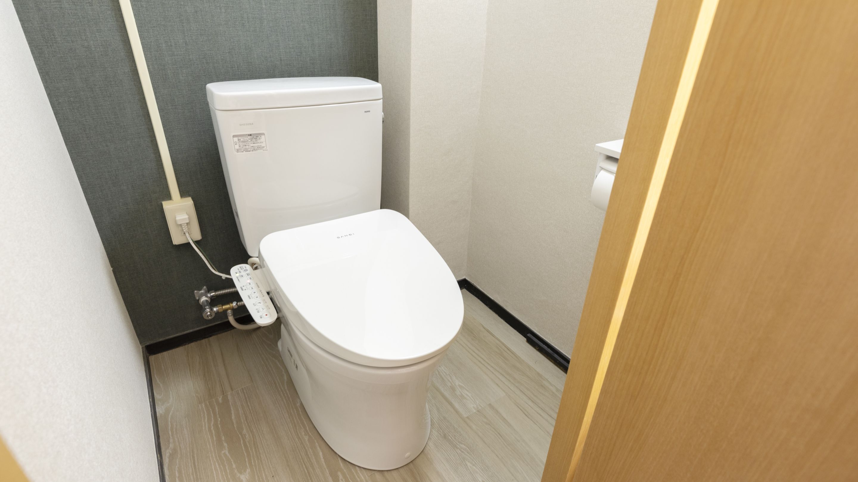 A small, modern bathroom with a toilet, a control panel, and a toilet paper holder.