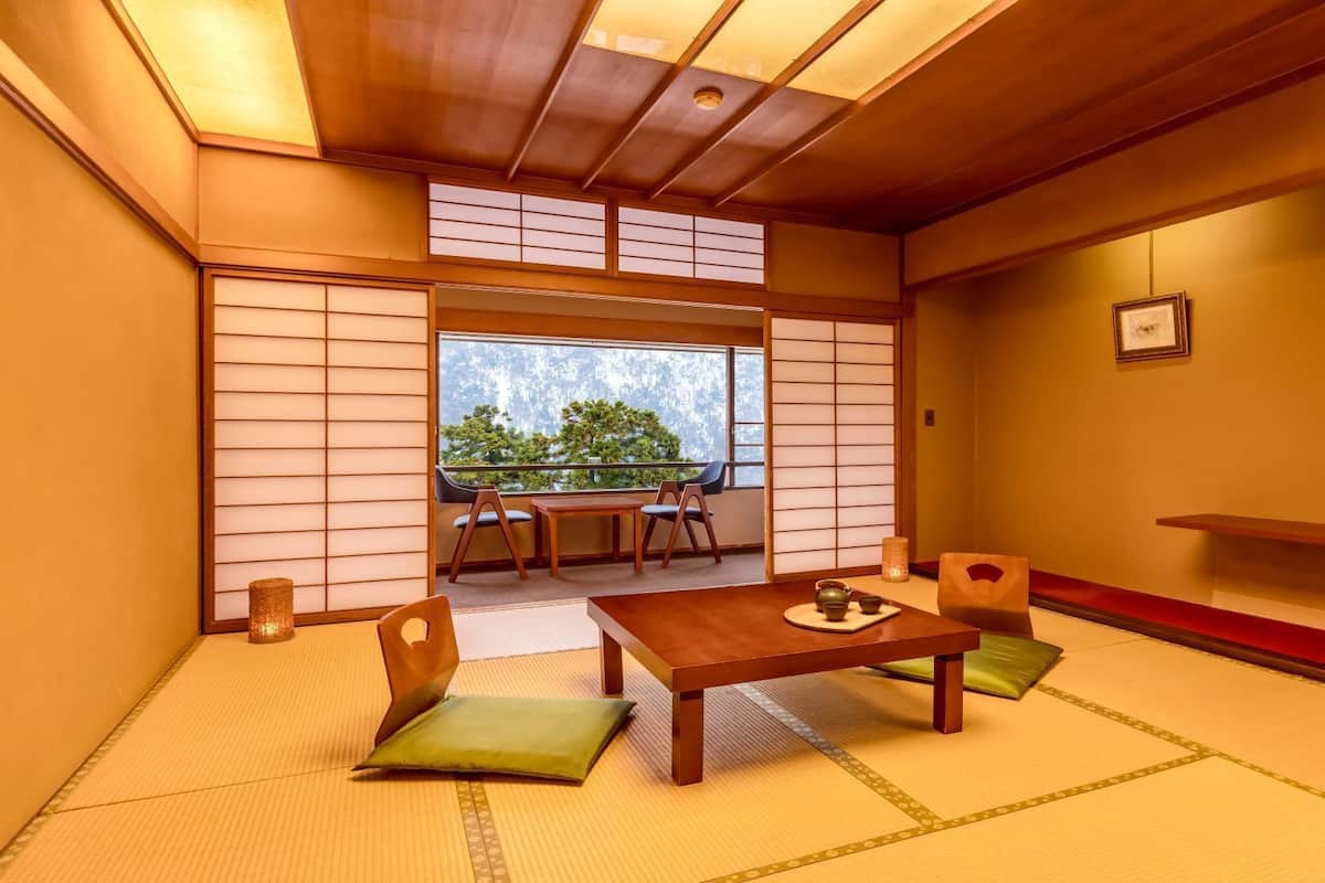 Ein traditioneller japanischer Raum mit Tatami-Bodenbelag, einem niedrigen Tisch mit Tee-Service und Schiebetüren.
