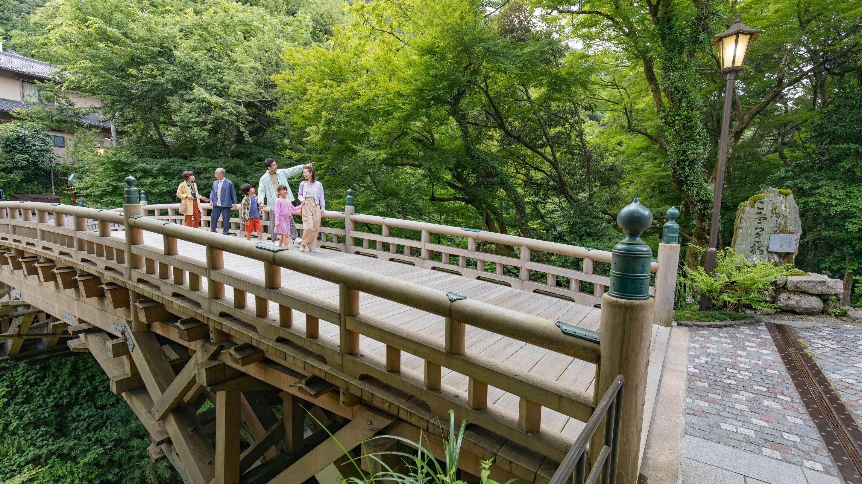 A wooden bridge with a stone pathway leading to a stone lantern.