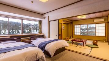 A traditional Japanese-style room with tatami flooring, a low table with a tea set, and a bed with multiple pillows.