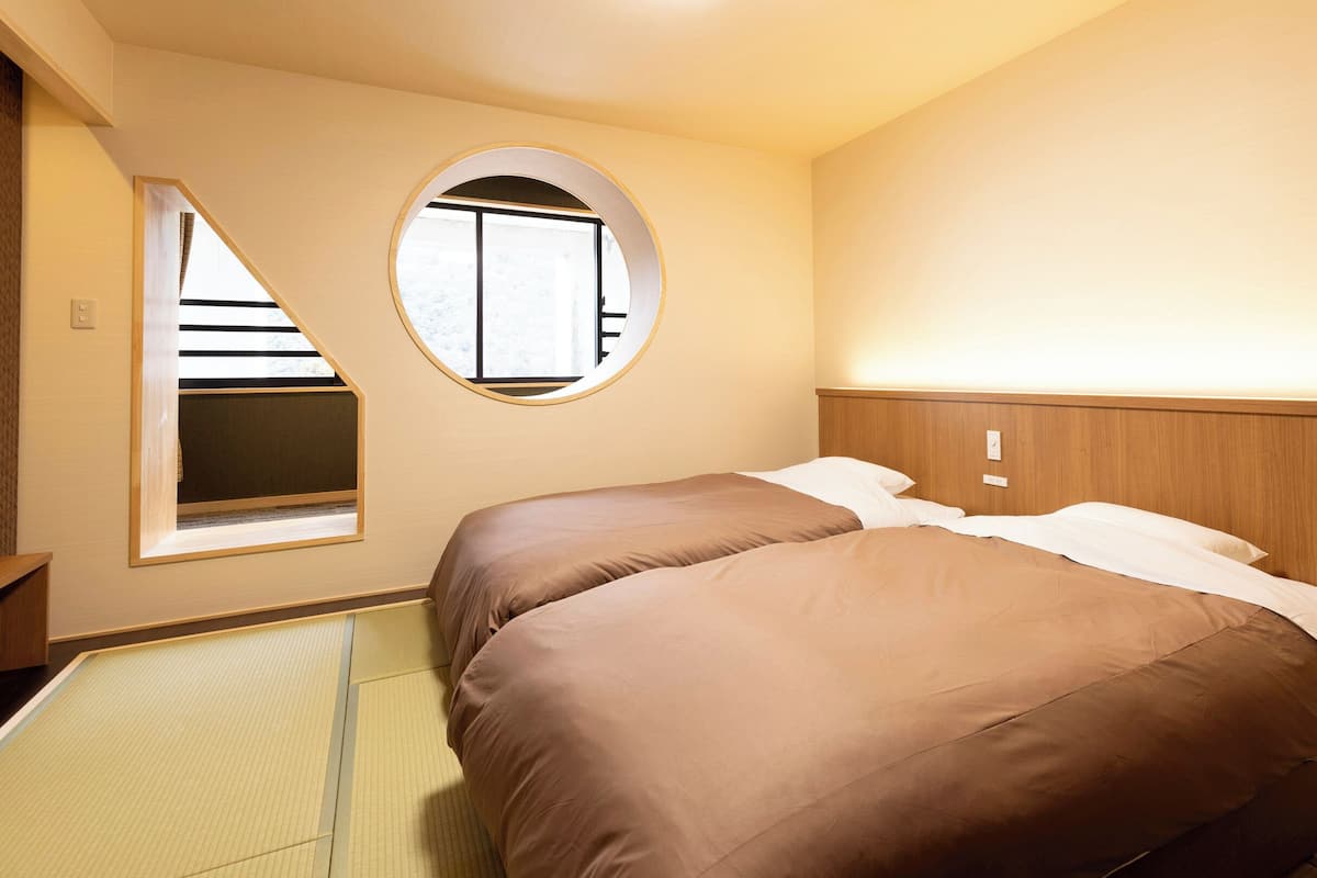Ein Schlafzimmer mit einem Bett, einem runden Fenster und einem hölzernen Kopfteil.