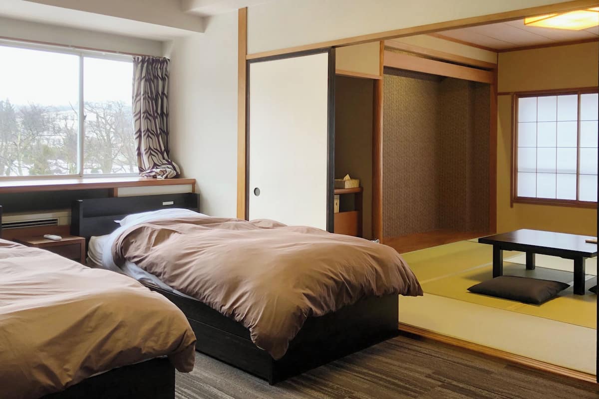 Ein Hotelzimmer mit zwei Betten, einem Schreibtisch und einer Schiebetür zu einem begehbaren Kleiderschrank.