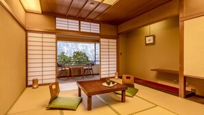 A traditional Japanese room with tatami flooring, a low table, and chairs. - Ooedo Onsen Monogatari Premium Yamanaka Grand Hotel (Kaga)