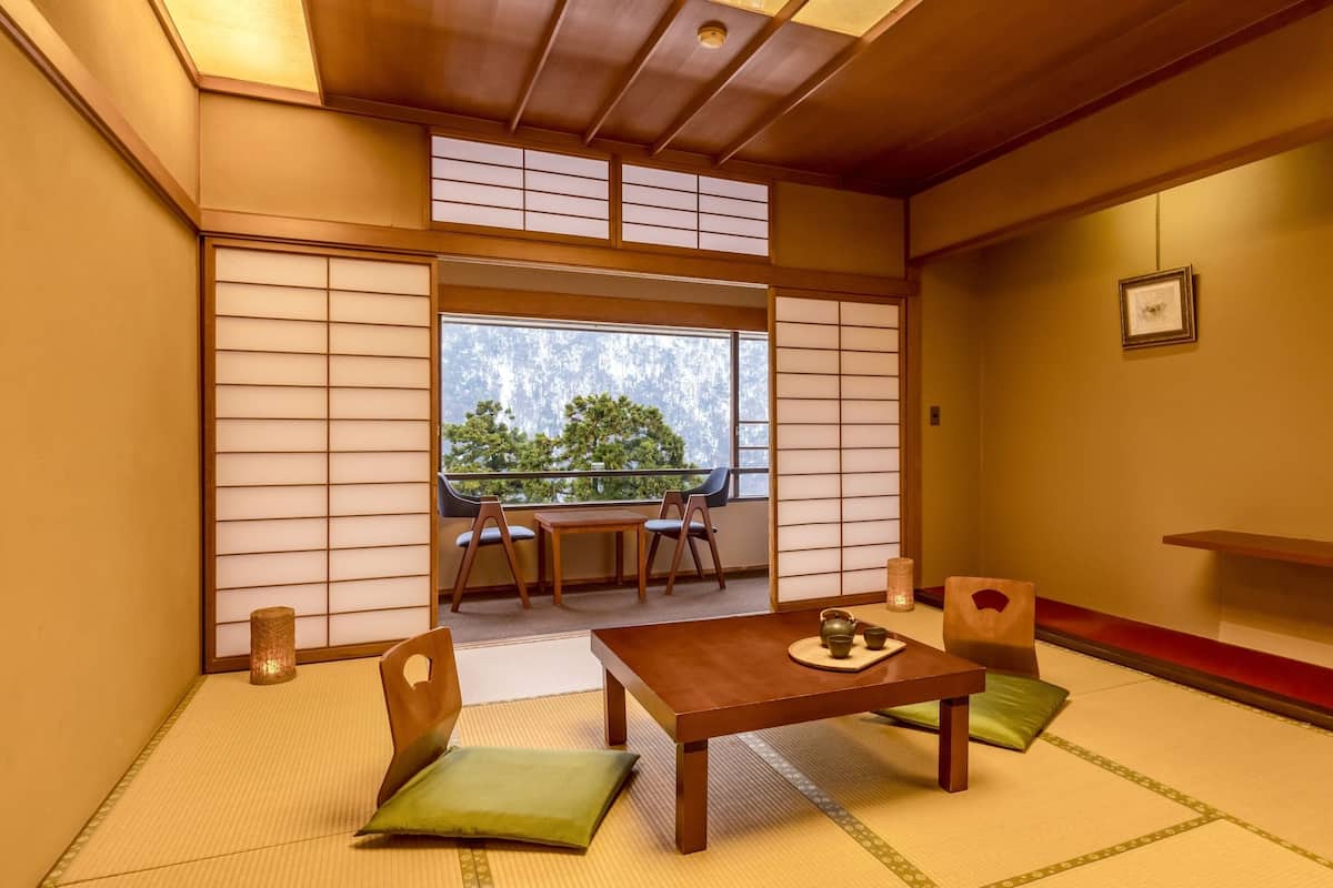 Ein traditioneller japanischer Raum mit Tatami-Boden, einem niedrigen Tisch und Stühlen.