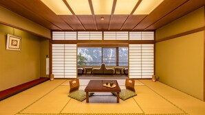 A traditional Japanese room with tatami flooring, a low wooden table, cushions, and sliding shoji screens. - Ooedo Onsen Monogatari Premium Yamanaka Grand Hotel (Kaga)