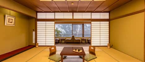 A traditional Japanese room with tatami flooring, a low wooden table, cushions, and sliding shoji screens.