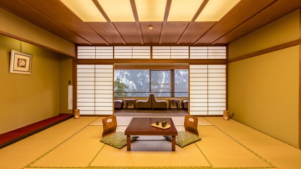 Una habitación japonesa tradicional con suelo de tatami, una mesa de madera baja, cojines y puertas correderas shoji.