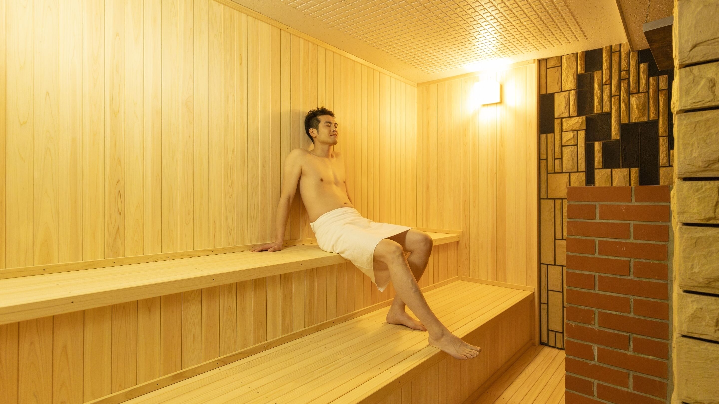 Un sauna avec des bancs en bois et un mur en pierre.