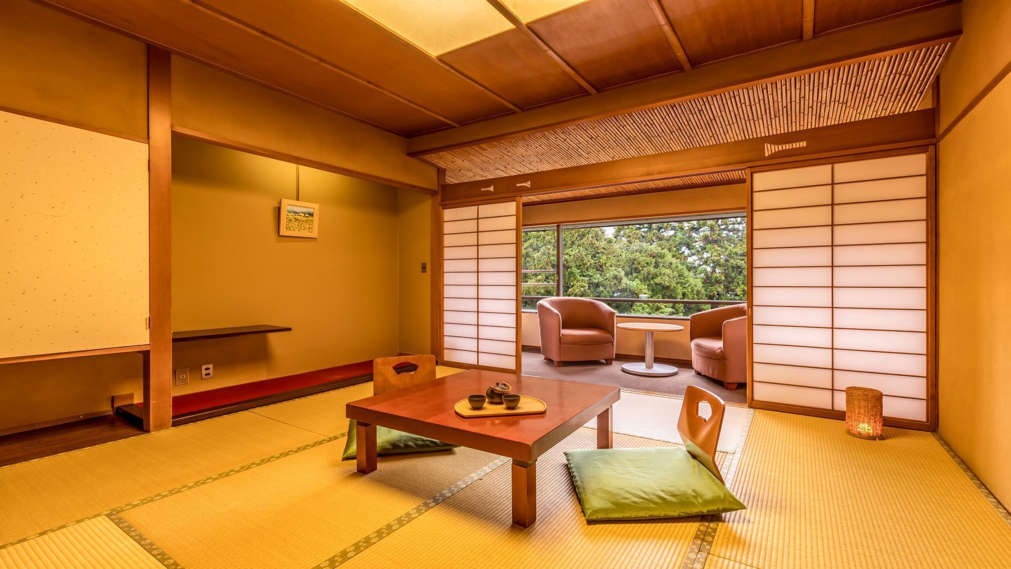 A traditional Japanese room with tatami flooring, a low table with a tea set, and a view of greenery outside.