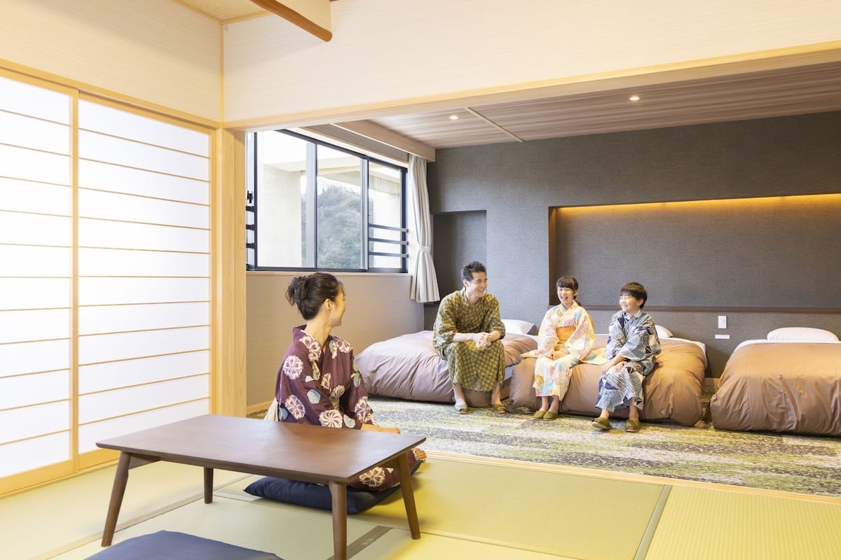 Ein traditioneller japanischer Raum mit Tatami-Böden, einem niedrigen Tisch und einer Couch mit Kissen.