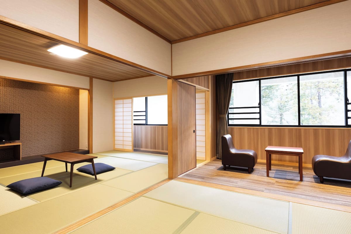 Ein traditioneller japanischer Raum mit Tatami-Bodenbelag, einem Fernseher und Holzmöbeln.