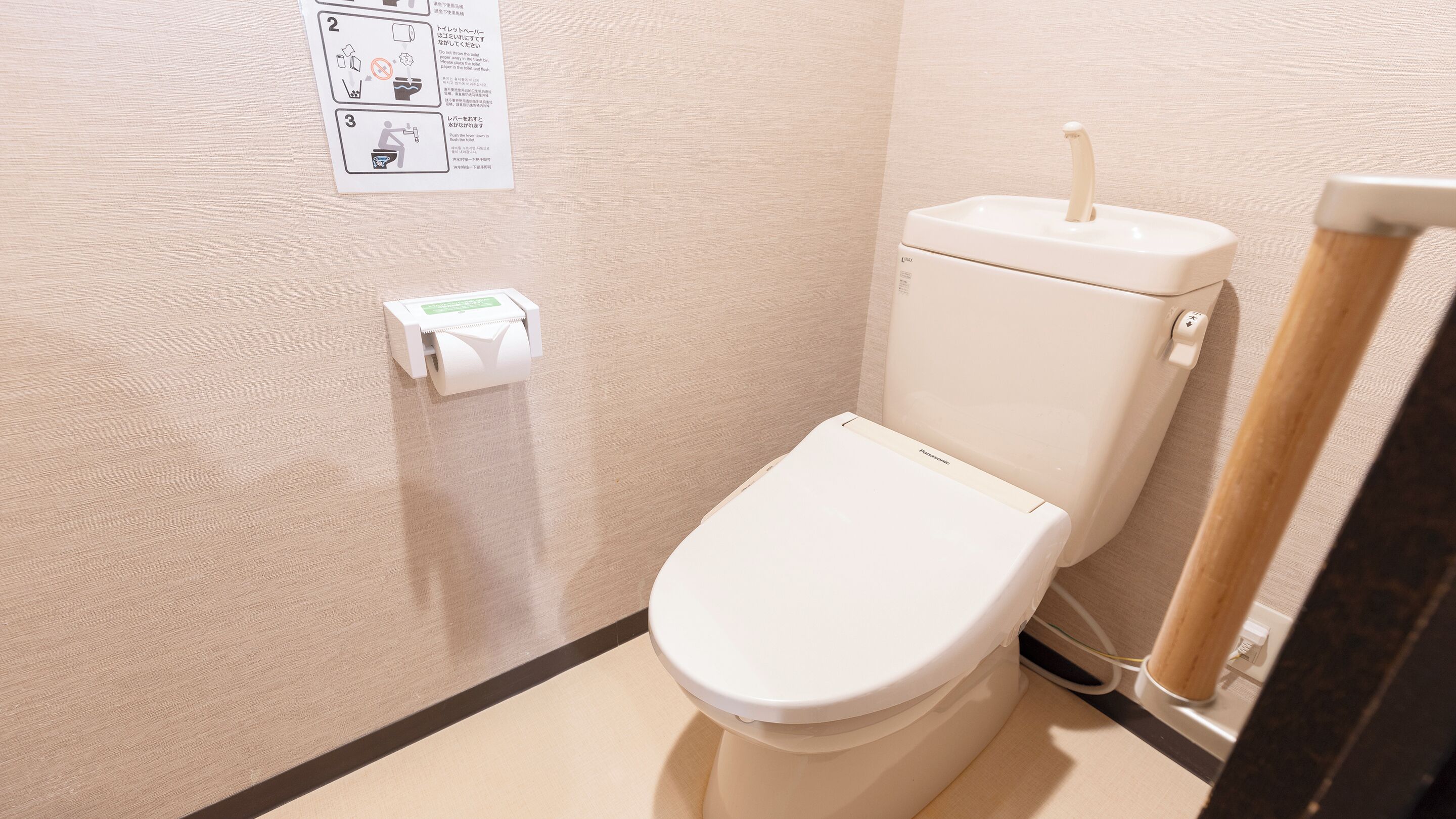 Un baño pequeño y limpio con inodoro, dispensador de toallas de papel y rollo de papel higiénico.