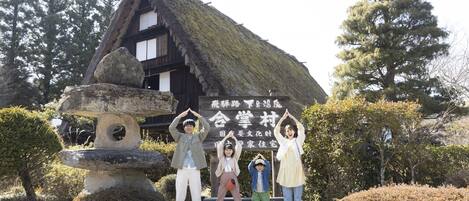 Un edificio japonés tradicional con techo de paja y un farol de piedra en primer plano.