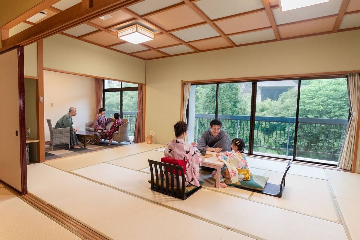 Um quarto japonês tradicional com tatames, uma porta deslizante e uma varanda com vista para o verde.