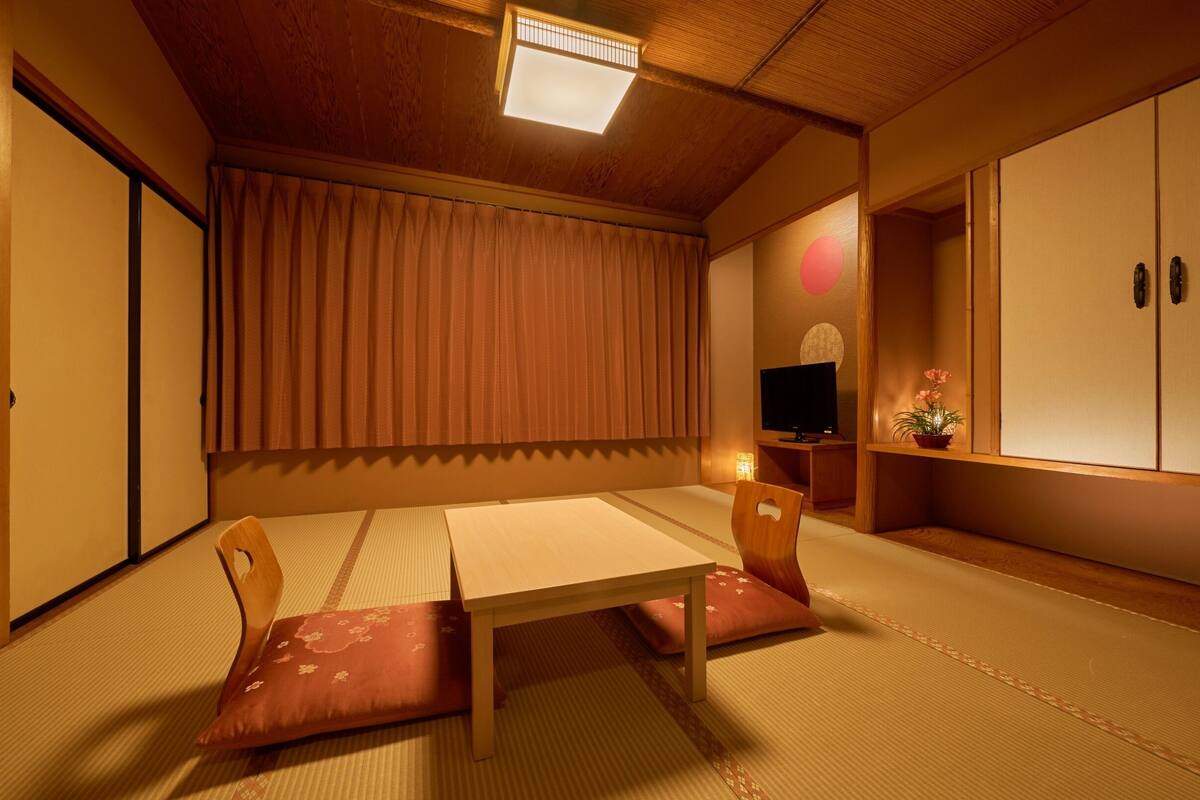 Um quarto japonês tradicional com piso de tatame, uma mesa baixa e portas deslizantes.
