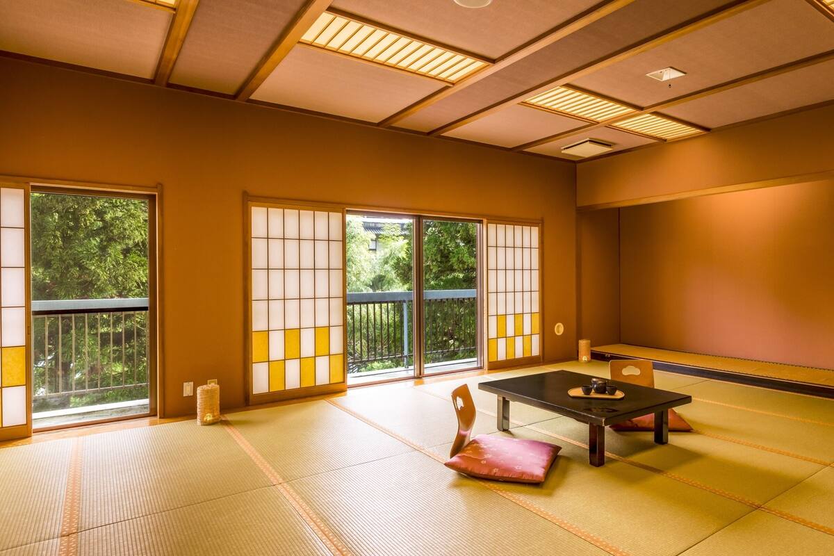 Um quarto japonês tradicional com tatames, portas deslizantes e uma mesa baixa com almofada.