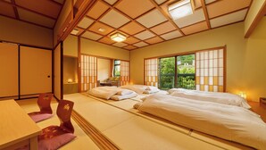 Perinteinen japanilaistyylinen huone, jossa on tatamimatto, matala puukatto ja liukuvat ovet. Huoneessa on kaksi sänkyä valkoisilla vuodevaatteilla sekä pieni pöytä ja tuoli.