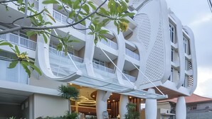 A modern hotel with a unique architectural design, featuring a curved facade, multiple balconies, and a well-lit entrance. - Bedrock Hotel (Kuta)