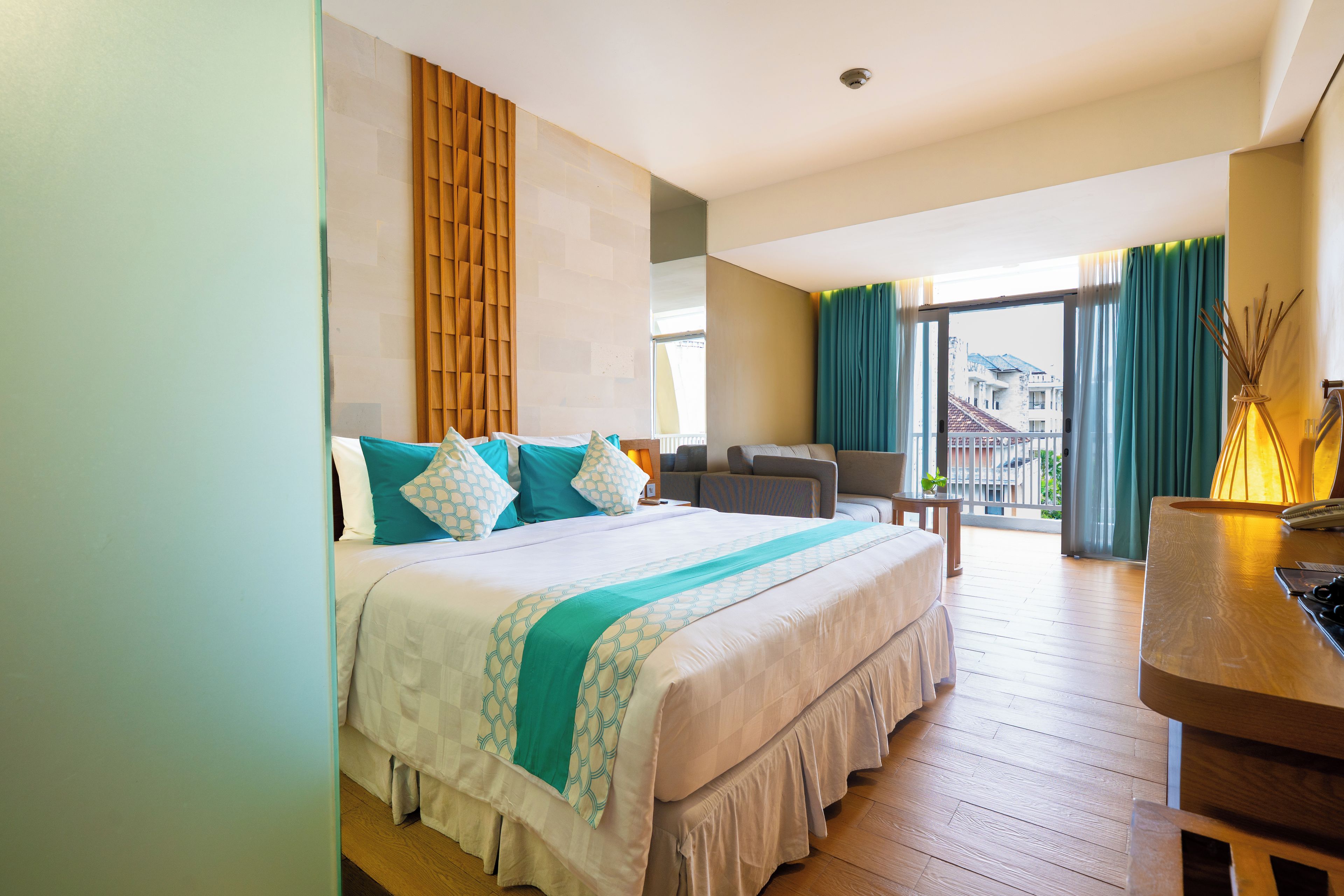 Habitación de hotel con cama, escritorio, silla, vista al exterior y cortinas.
