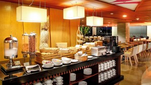 A buffet setup with various food items, a coffee machine, and seating arrangements. - Bedrock Hotel (Kuta)