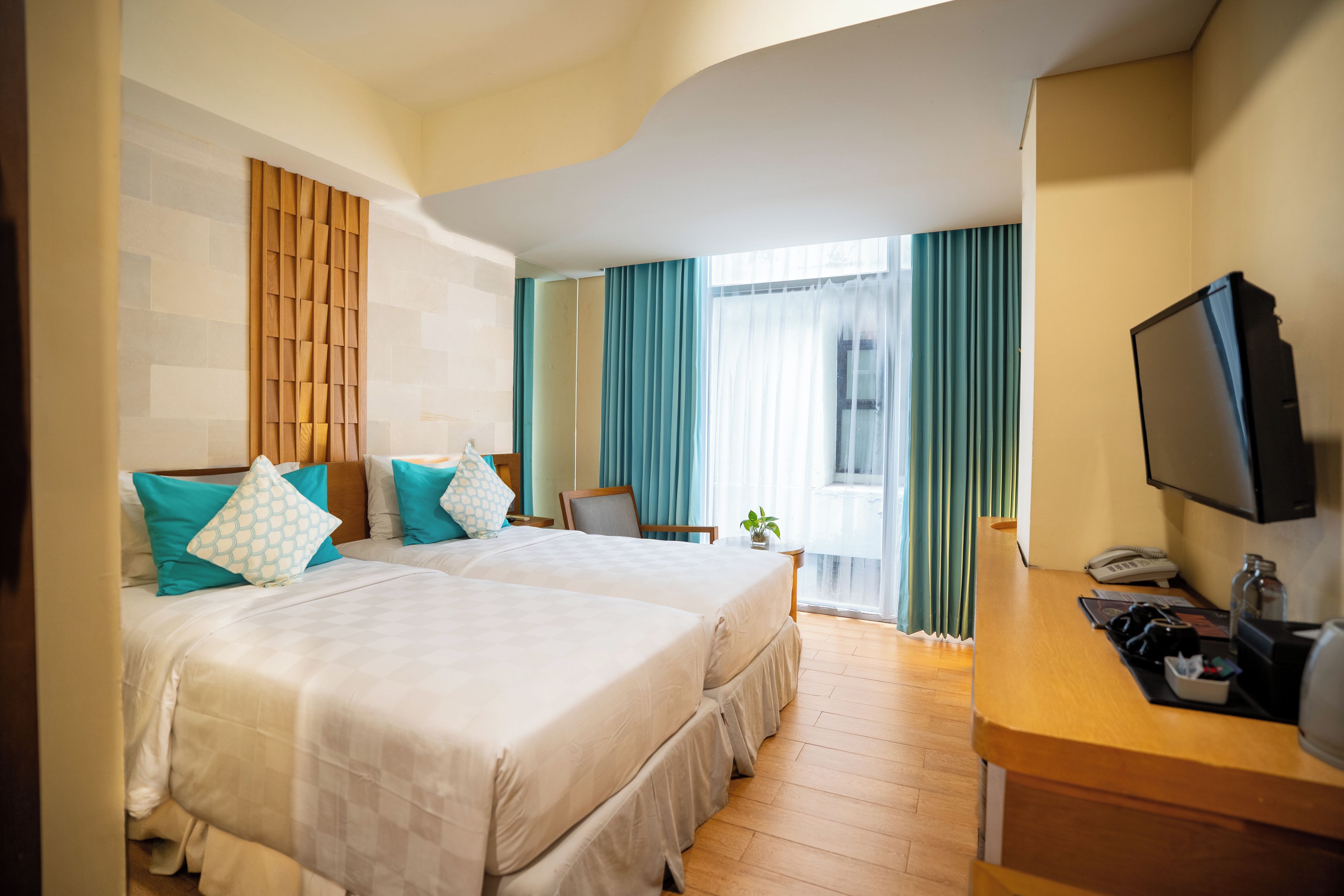 A hotel room with two beds, a desk with a telephone, and a television.