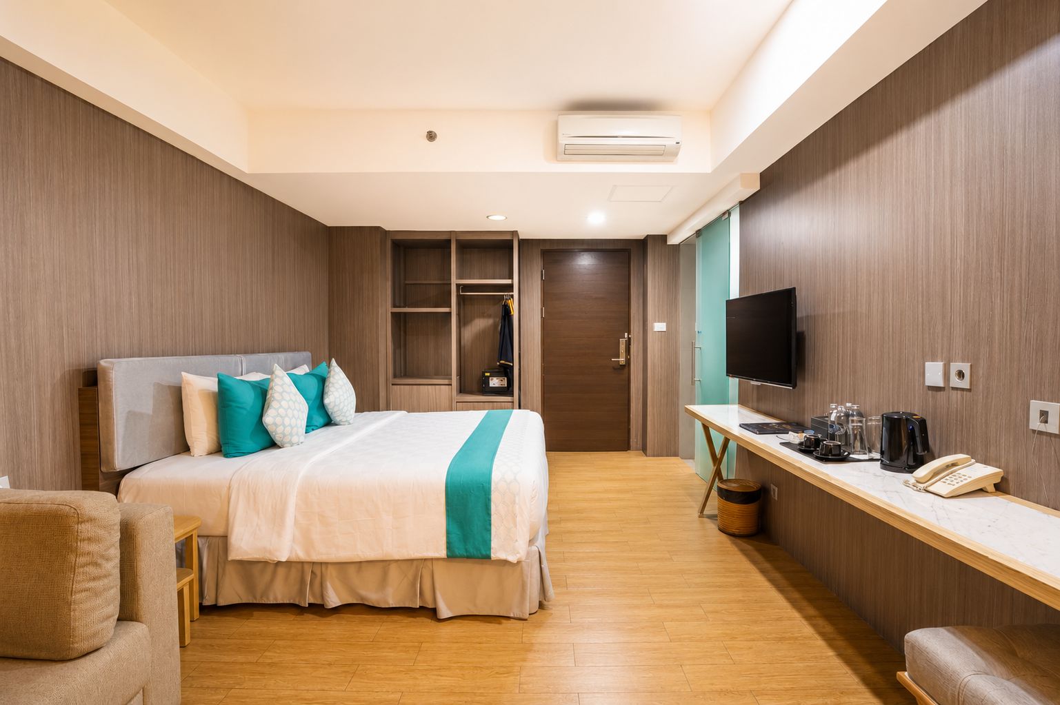 Una habitación de hotel con cama, escritorio con teléfono, televisión y armario.