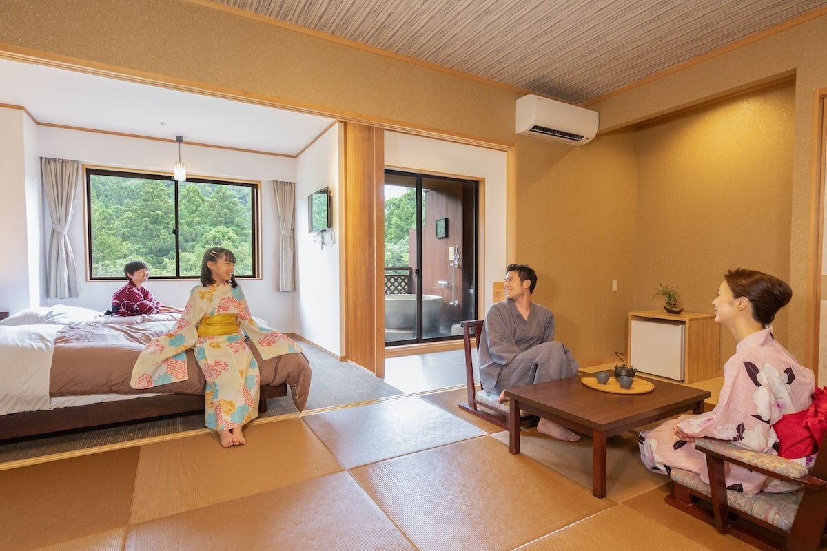 A traditional Japanese-style room with tatami flooring, a sliding door leading to a balcony, and a bed with a view of greenery.