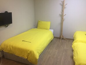 A room with a bed covered in yellow bedding, a wooden coat rack, and a flat-screen TV mounted on the wall. - 24 Guesthouse Seoul Cheongryangri (Seoul)