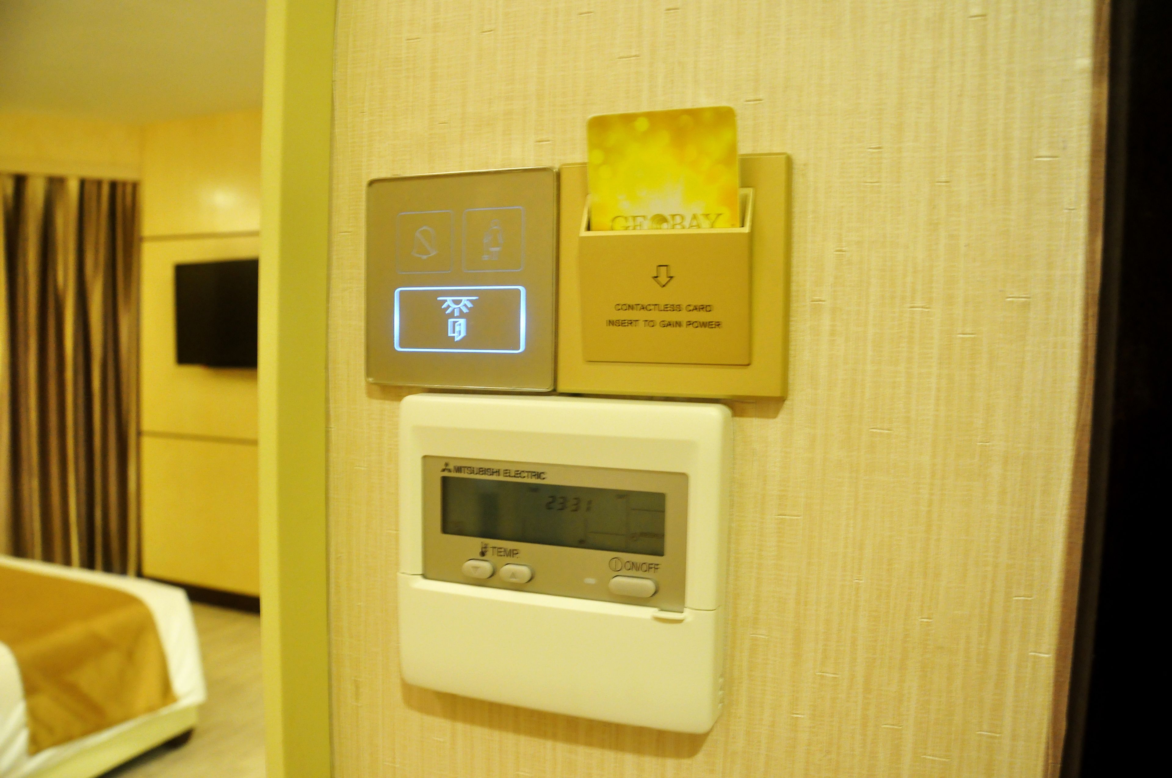 A wall-mounted thermostat with a digital display, a card slot, and a contactless card reader.