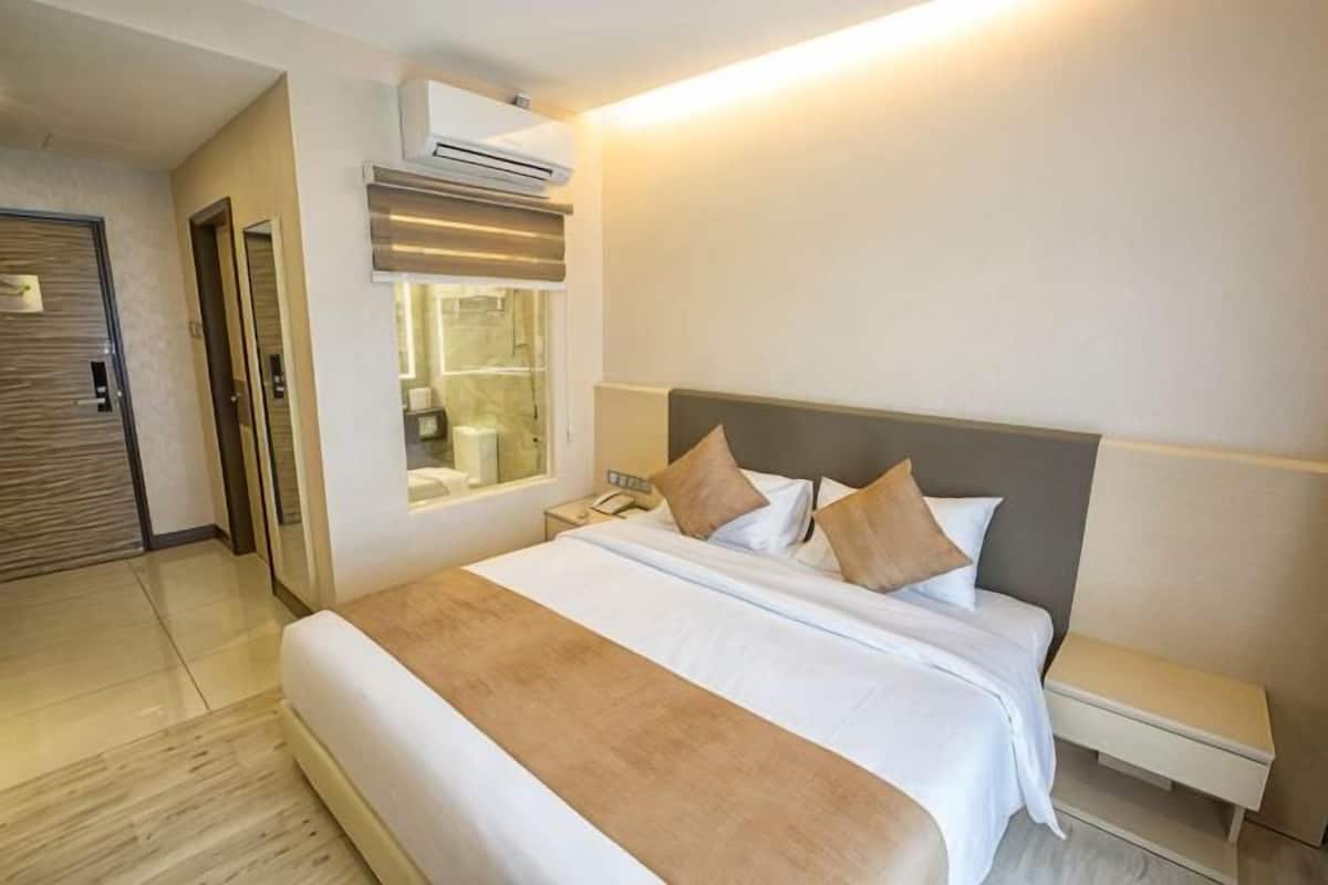 Quarto de hotel com uma cama grande, mesa de cabeceira e um espelho.