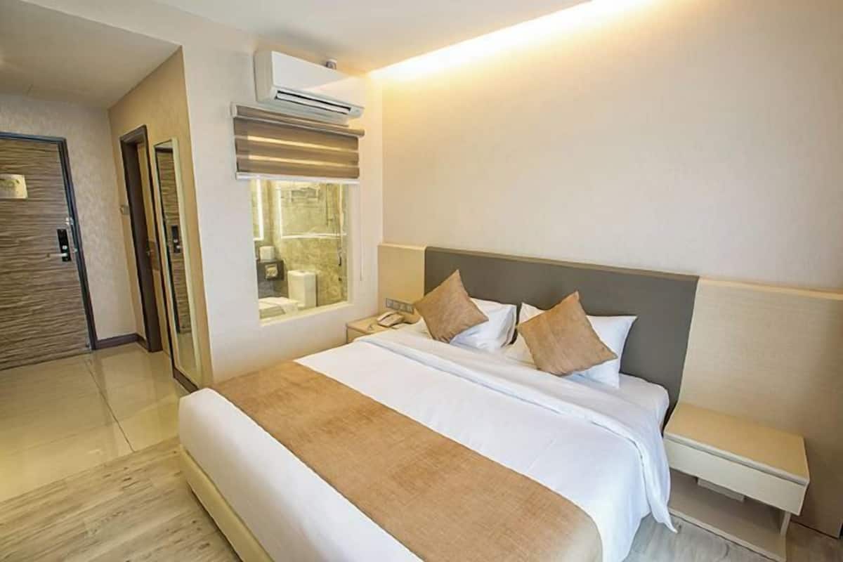 Une chambre d’hôtel avec un grand lit, une table de chevet et une fenêtre.