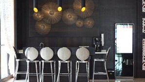 A modern bar area with a dark wall, a large mirror, and a unique ceiling light fixture. - Geobay Hotel (Johor Bahru)
