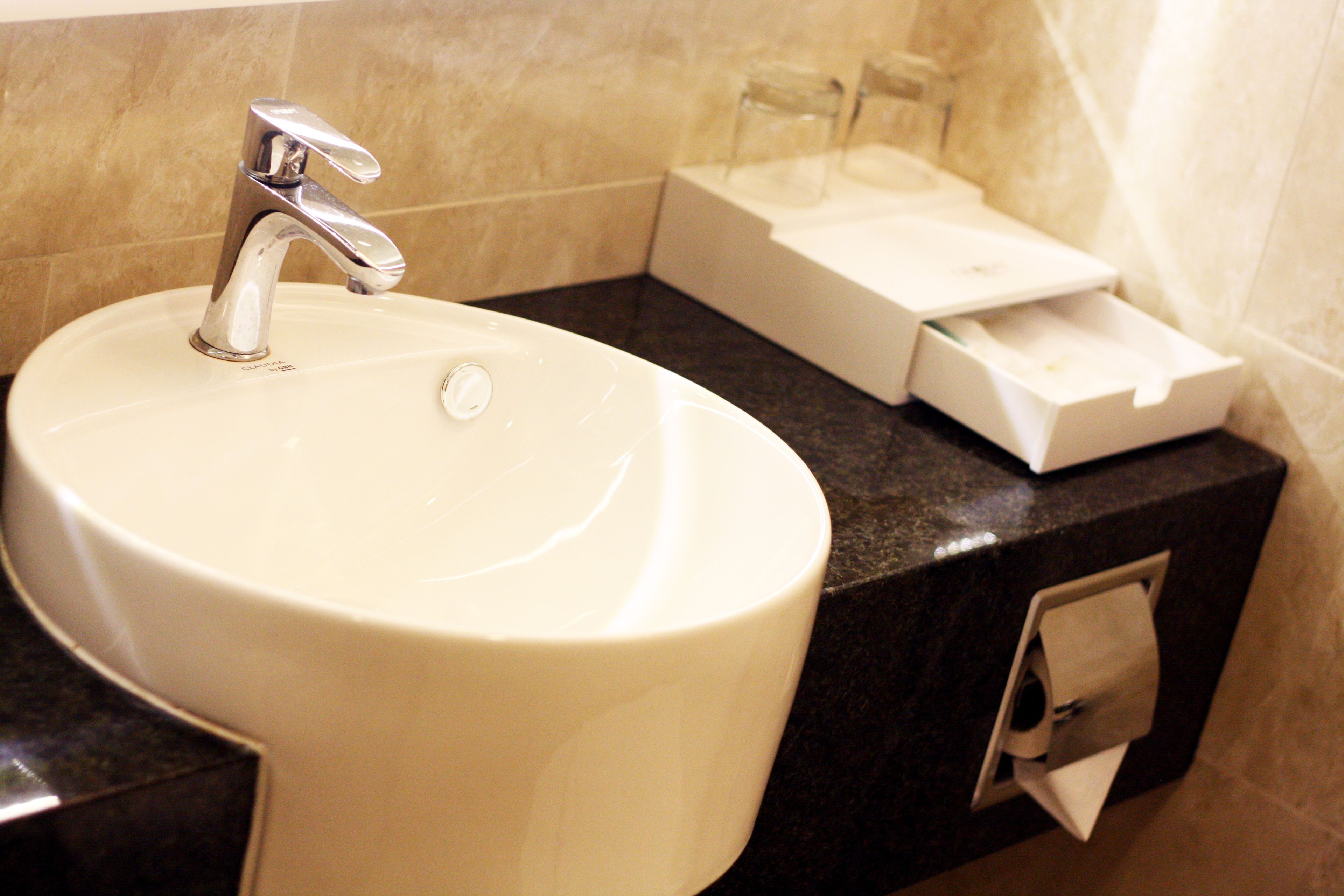 A bathroom sink with a faucet, a soap dispenser, and a paper towel dispenser.