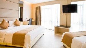 A hotel room with a large bed, a desk, a chair, a TV mounted on the wall, and a window with curtains. - Geobay Hotel (Johor Bahru)