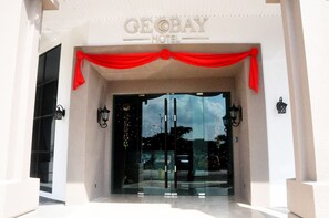 The entrance of the GeBay Hotel with a red draped entrance and glass doors. - Geobay Hotel (Johor Bahru)