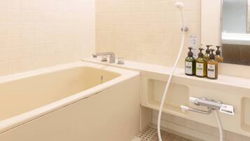 Une salle de bain avec une baignoire, une douche et un lavabo. On peut voir des bouteilles de shampoing et d’après-shampoing sur le lavabo.