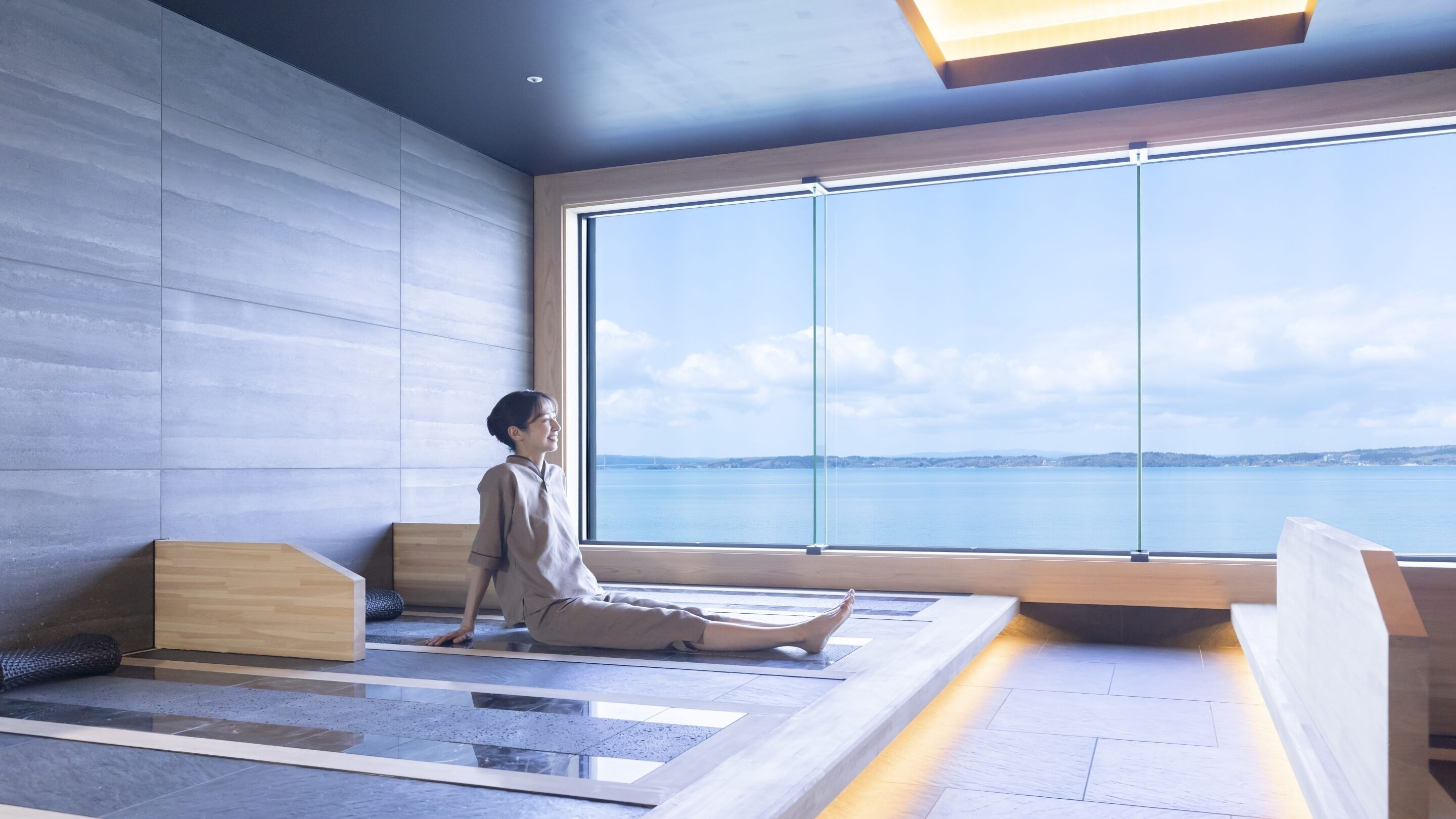 A modern room with a large window, a yoga mat, and a wooden bench.