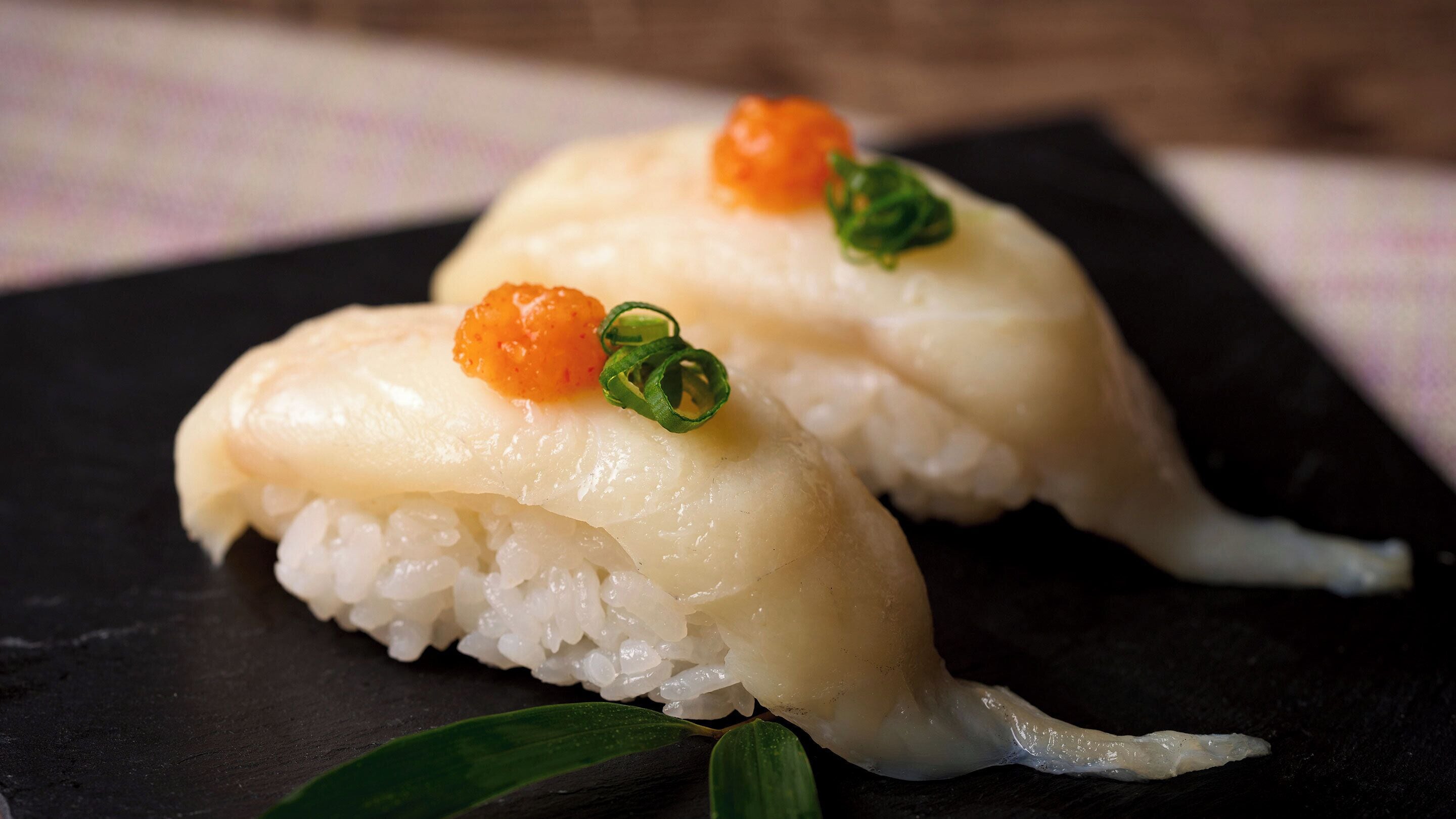 A sushi dish with rice and fish on a black plate.