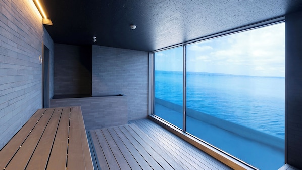 A modern interior with a wooden deck, a seating area, and a large window overlooking a body of water. - TAOYA Wakura (Nanao)