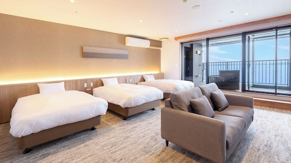 Une chambre d’hôtel avec deux lits, un canapé et une grande fenêtre donnant sur un beau paysage.