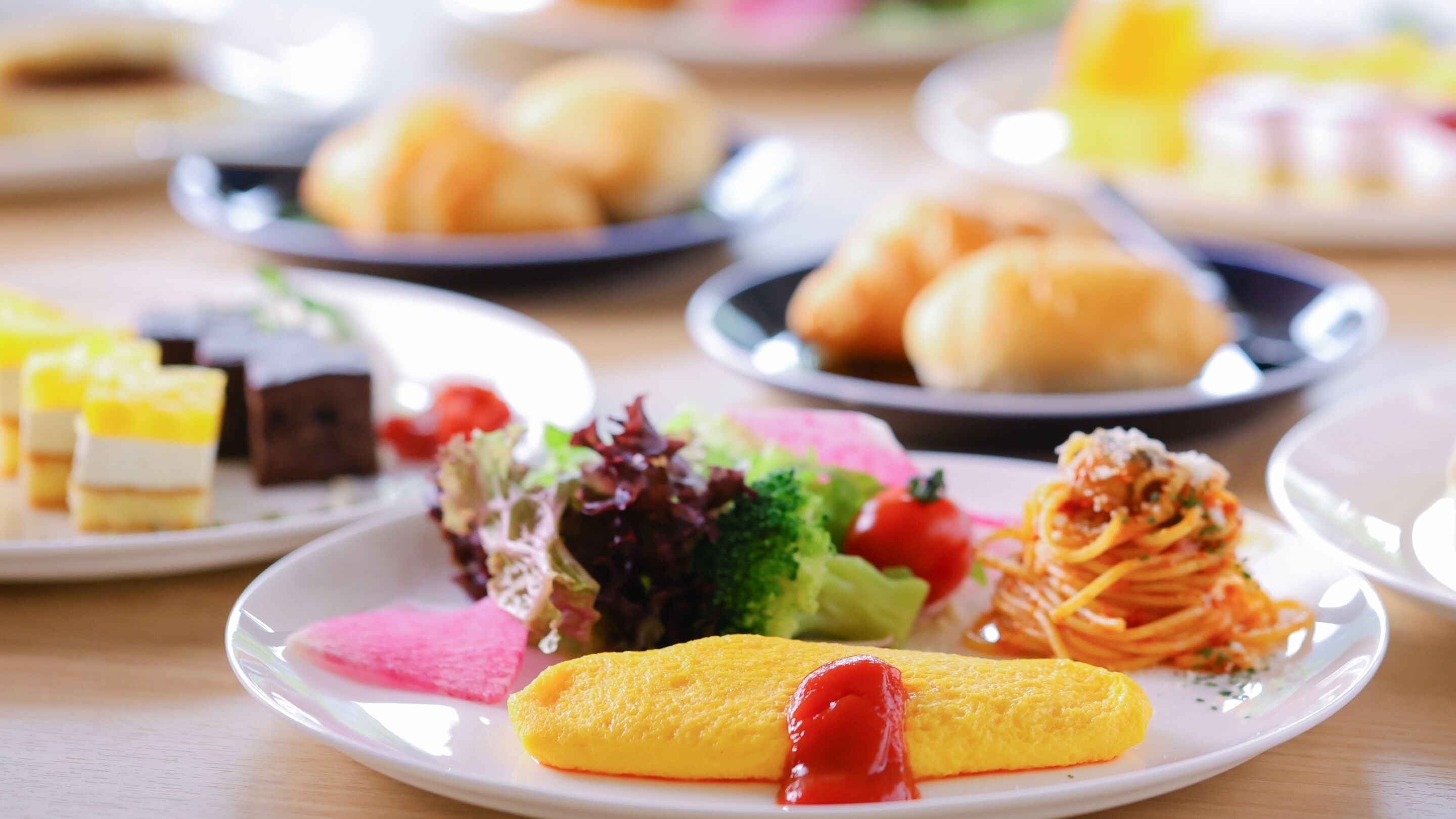 A variety of dishes on plates, including pasta, a rolled omelette, and a salad.