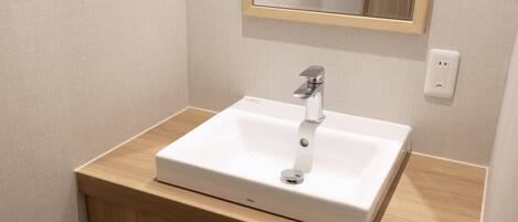 A bathroom with a white sink, wooden vanity, and a mirror above the sink.
