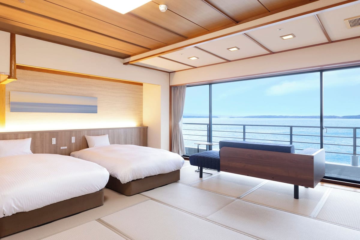 Une chambre d’hôtel moderne, dotée de deux lits, d’un bureau et d’une grande fenêtre donnant sur la mer.