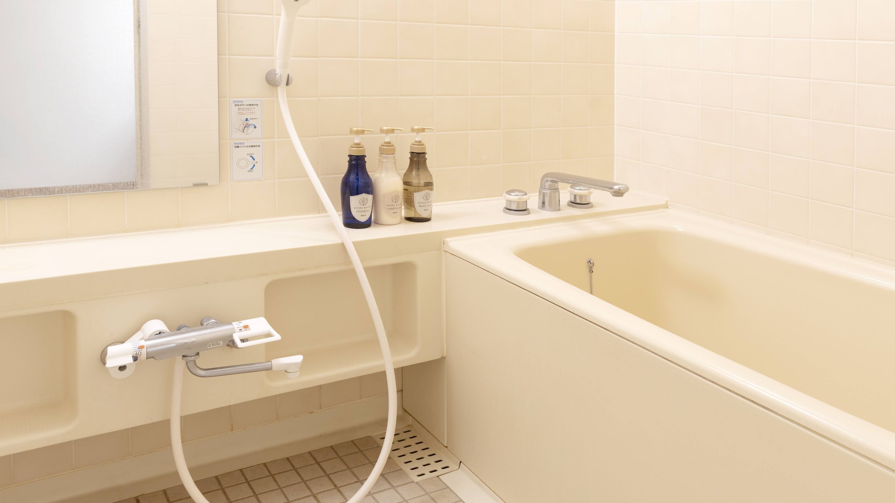 A bathroom with a bathtub, a shower, and a toilet. There are bottles of shampoo and conditioner on the counter.