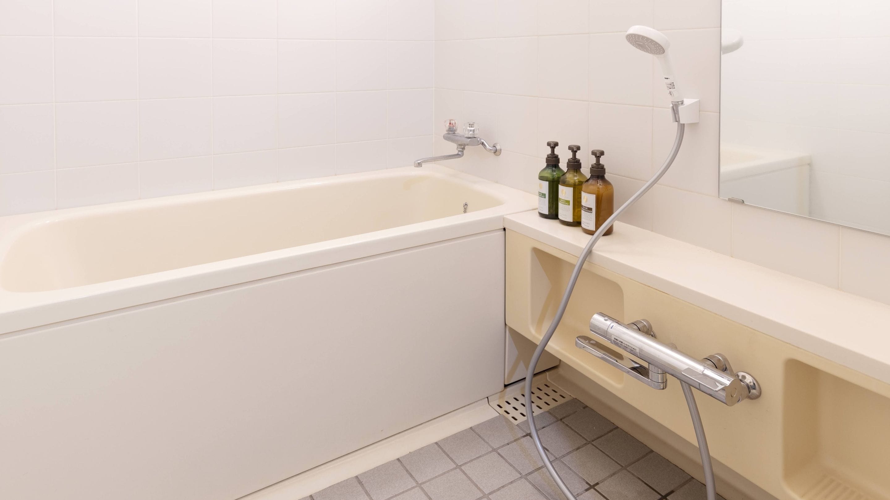 Un baño con bañera, ducha y lavamanos con dispensadores de jabón.