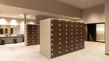 A hotel bathroom with multiple lockers, a sink area, and a mirror.