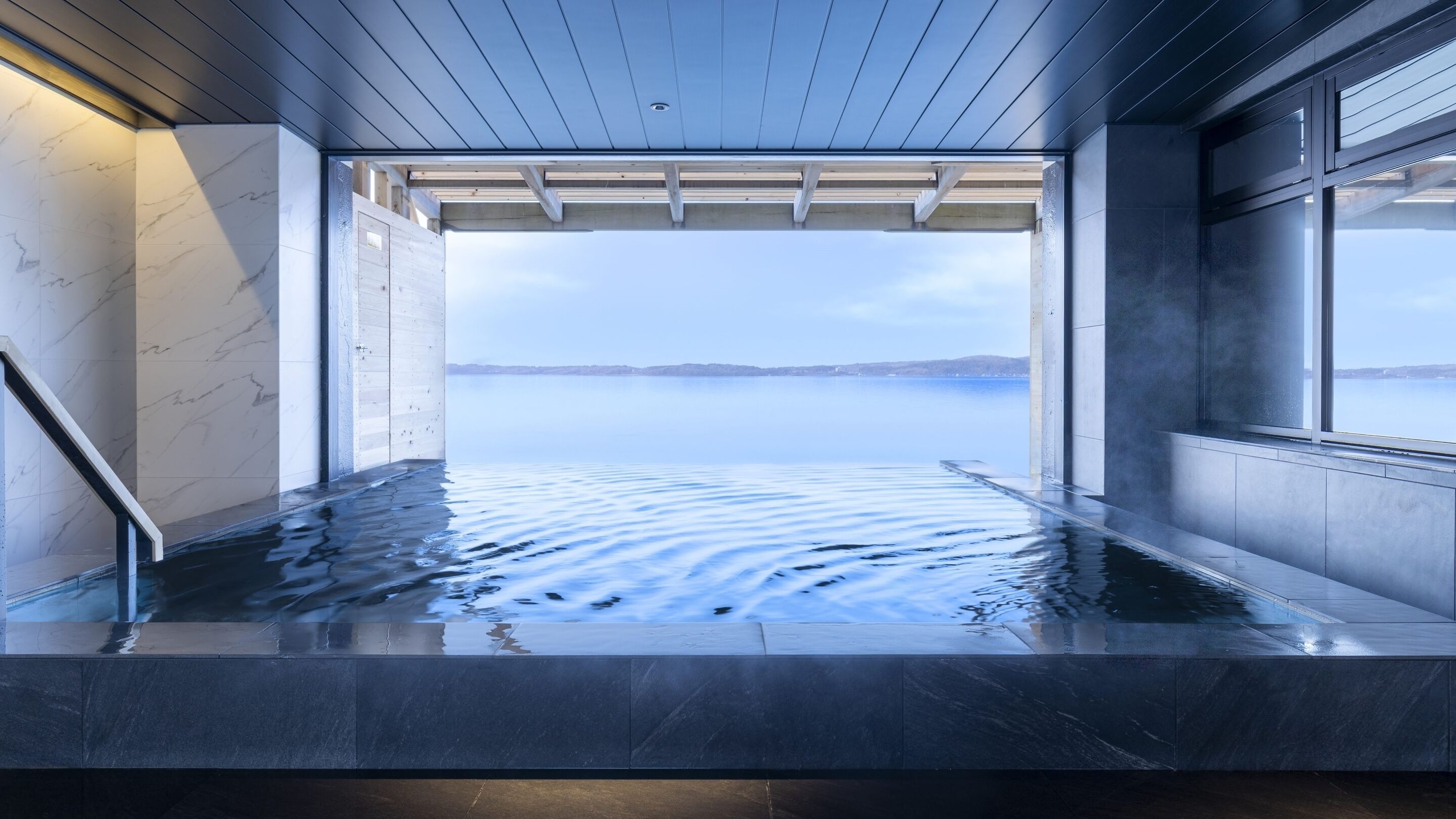 Un moderno espacio de spa con vistas a una masa de agua tranquila.