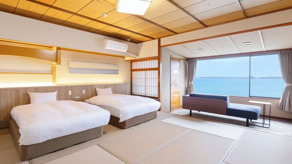 Ein Hotelzimmer mit zwei Betten, Meerblick und einer traditionellen japanischen Schiebetür.