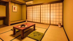 A traditional Japanese room with tatami flooring, a low wooden table, a shoji screen, and a ceiling light fixture. - Ooedo Onsen Monogatari Wanwan Resort Awazu (Komatsu)